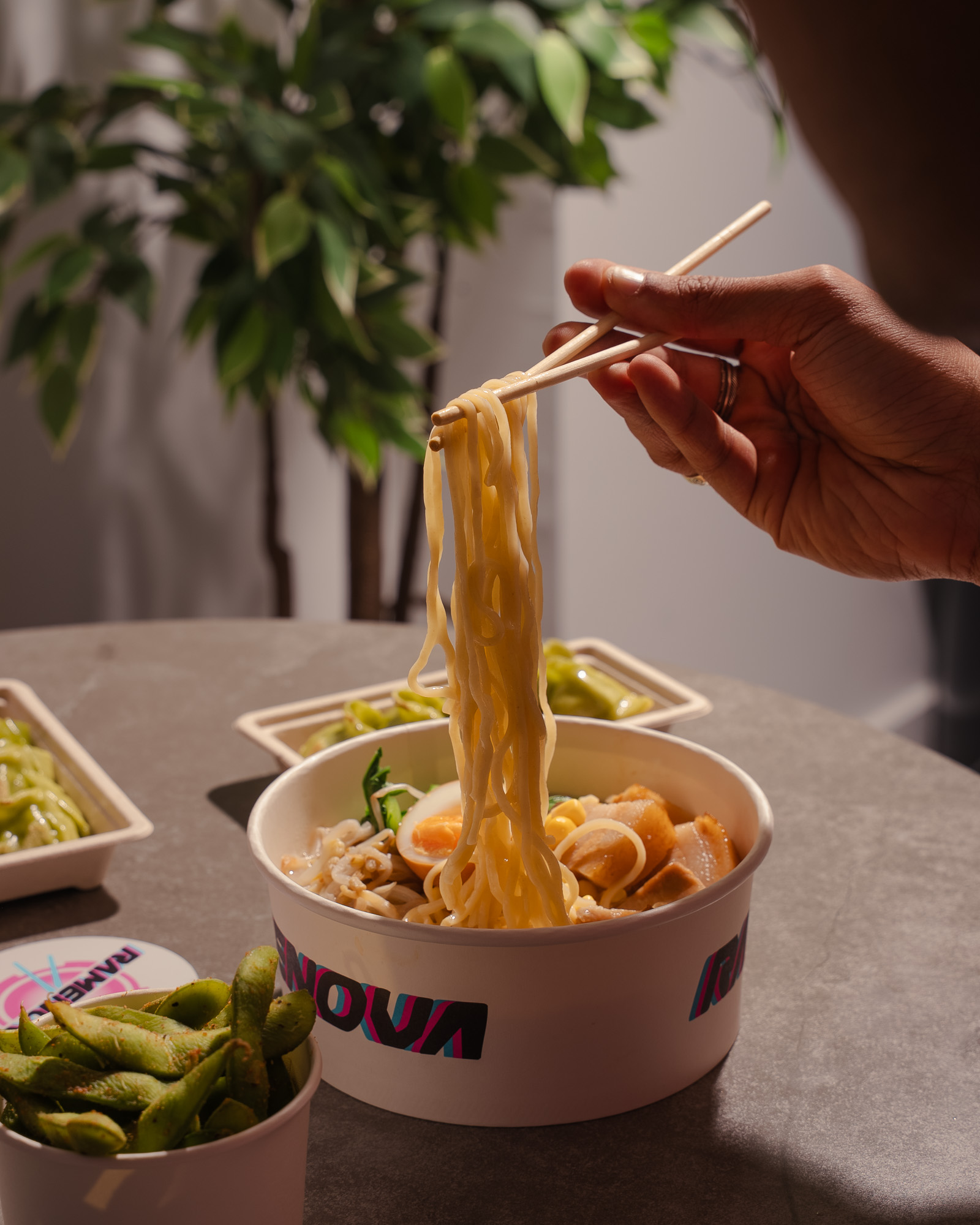 Noodles lifted from a Ramenova takeaway bowl with chopsticks