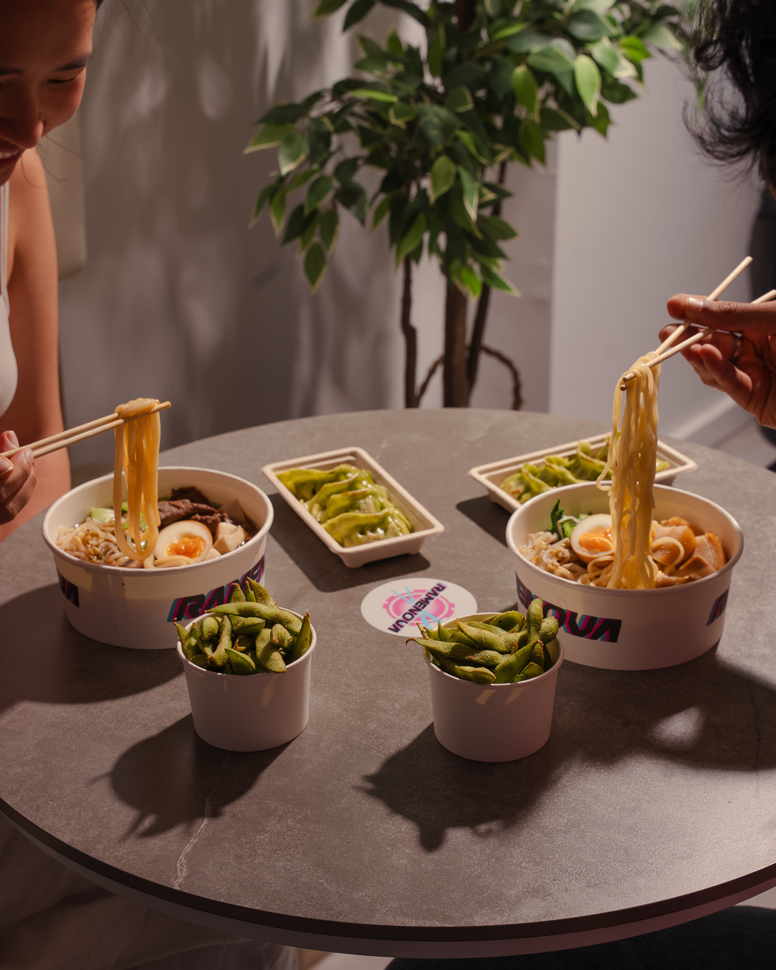 Two people sharing ramen, gyoza and edamame